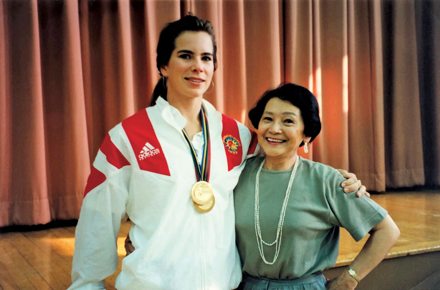 Photo of Marnie McBean with former teacher Mary Matsui. Both are smiling. Marnie has gold medals around her neck.